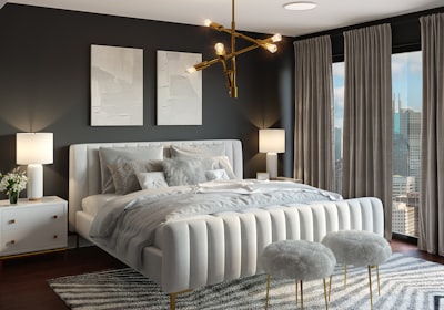 A gray bedroom with an upholstered double bed, a matching lamp on each side and a city window