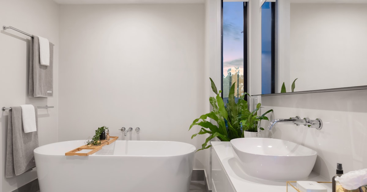A bathroom with a freestanding oval tub, a potted plant and a tall window